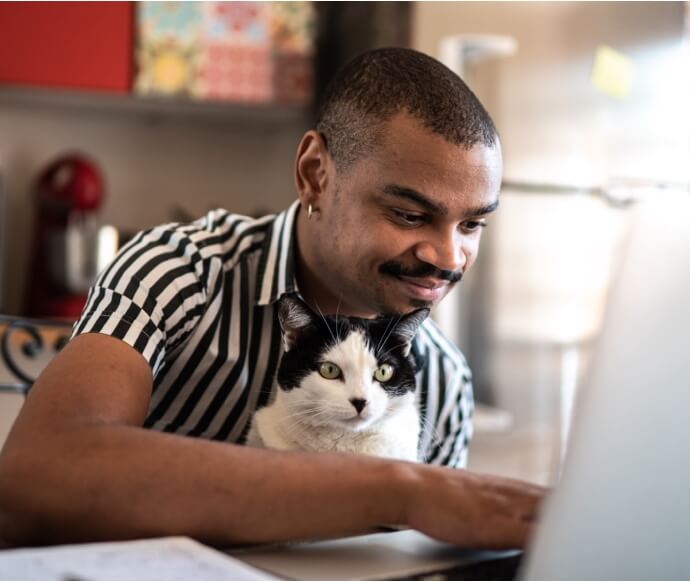 Homme utilisant un ordinateur portable en portant un chat